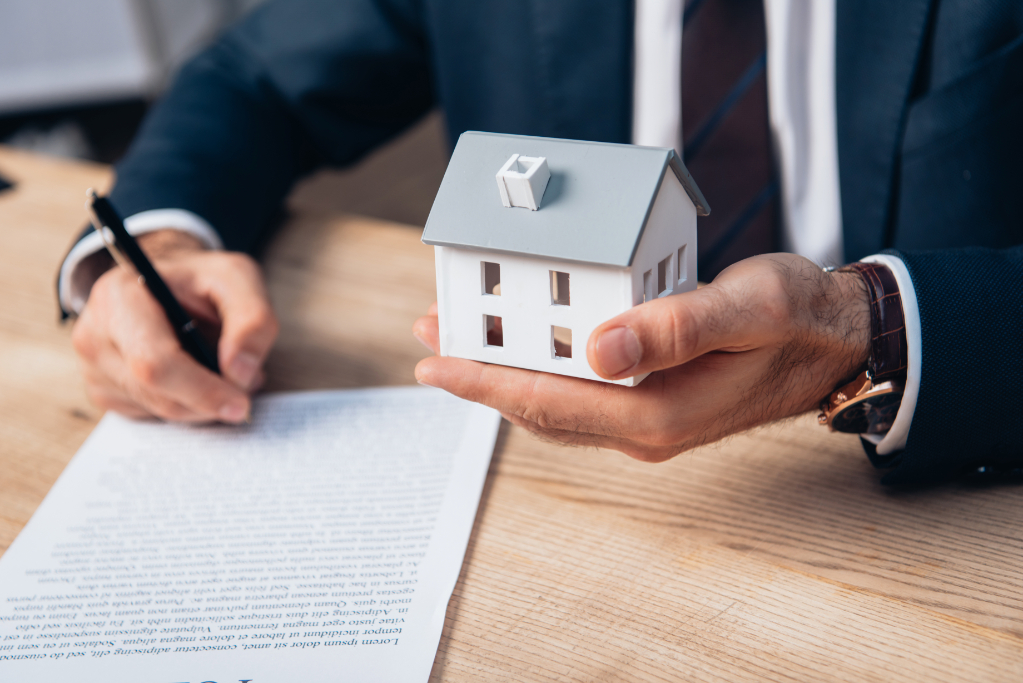 View lawyer holding house and signing contract